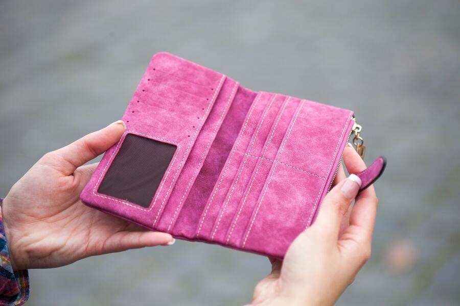 Una persona sostiene abierta una cartera vacía de ante rosa con varias ranuras para tarjetas y una ventanilla transparente para el DNI, tal vez reflexionando sobre el impacto de la prestación compensatoria, mientras está de pie al aire libre sobre una superficie gris borrosa. Una persona sostiene abierta una cartera vacía de ante rosa con varias ranuras para tarjetas y una ventanilla transparente para el DNI, tal vez reflexionando sobre el impacto de la prestación compensatoria, mientras está de pie al aire libre sobre una superficie gris borrosa.