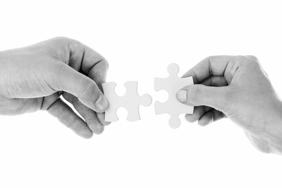 Dos manos sostienen piezas de puzzle blancas, cada una con una pieza. Las formas de las piezas sugieren que pueden encajar -como un exequátur que conecta dos sistemas jurídicos- sobre un fondo blanco liso.