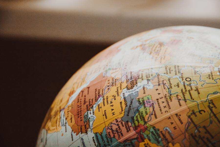 Primer plano de un globo terráqueo que muestra países de Europa, Oriente Medio y partes de Asia -regiones en las que se están desarrollando debates en torno a la gestación subrogada- con nombres y fronteras visibles sobre un fondo oscuro difuminado.