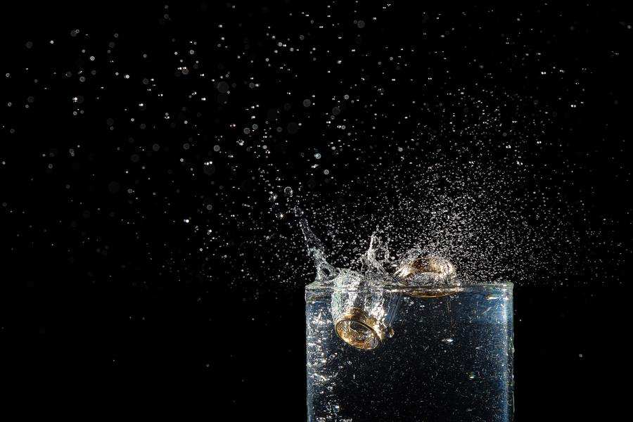 Un anillo de oro salpica un vaso de agua transparente sobre fondo negro, simbolizando cómo algunos optan por divorciarse sin pasar por el juzgado, haciendo los grandes cambios de la vida fuera de la sala. Gotas de agua y burbujas quedan suspendidas en el aire. Un anillo de oro salpica un vaso de agua transparente sobre fondo negro, simbolizando cómo algunos optan por divorciarse sin pasar por el juzgado, haciendo los grandes cambios de la vida fuera de la sala. Gotas de agua y burbujas quedan suspendidas en el aire.