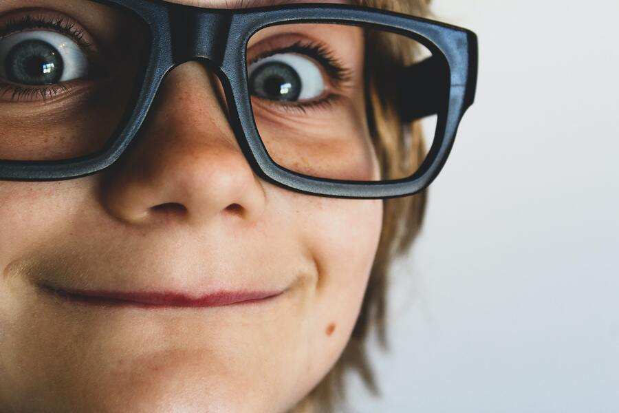 Primer plano del rostro de un niño con gafas negras de gran tamaño, sonriendo con los ojos muy abiertos y mirando directamente a la cámara: capta la inocencia de la juventud antes de que surjan preocupaciones como «a qué edad pueden decidir los hijos con quién quieren vivir tras el divorcio». Primer plano del rostro de un niño con gafas negras de gran tamaño, sonriendo con los ojos muy abiertos y mirando directamente a la cámara: capta la inocencia de la juventud antes de que surjan preocupaciones como "a qué edad pueden decidir los hijos con quién quieren vivir tras el divorcio".