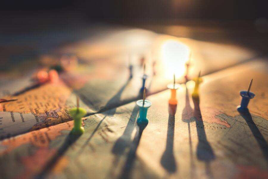 Un primer plano de un mapa con varias chinchetas de colores marcando ubicaciones, perfecto para ilustrar temas como la custodia compartida y vivir en el extranjero. El plano inclinado proyecta largas sombras de las chinchetas, realzadas por una cálida luz de fondo. Un primer plano de un mapa con varias chinchetas de colores marcando ubicaciones, perfecto para ilustrar temas como la custodia compartida y vivir en el extranjero. El plano inclinado proyecta largas sombras de las chinchetas, realzadas por una cálida luz de fondo.