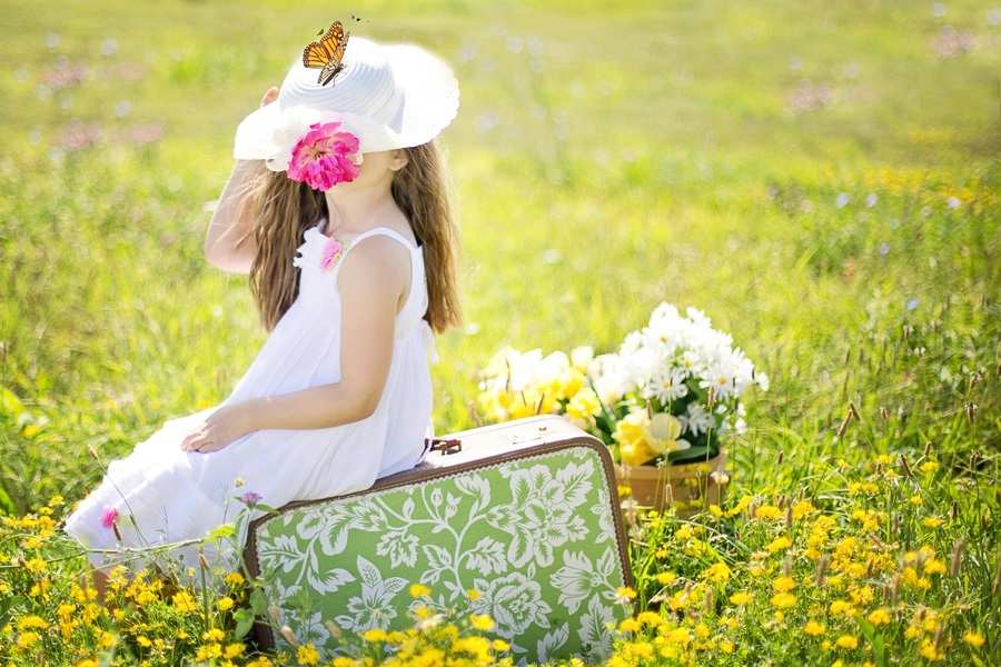 Una joven con vestido blanco y sombrero está sentada sobre una maleta de flores en un campo de flores amarillas, como esperando entregar ropa hijos divorcio; una mariposa descansa sobre su sombrero, y una cesta de flores está sobre la hierba a su lado. Una joven con vestido blanco y sombrero está sentada sobre una maleta de flores en un campo de flores amarillas, como esperando entregar ropa hijos divorcio; una mariposa descansa sobre su sombrero, y una cesta de flores está sobre la hierba a su lado.