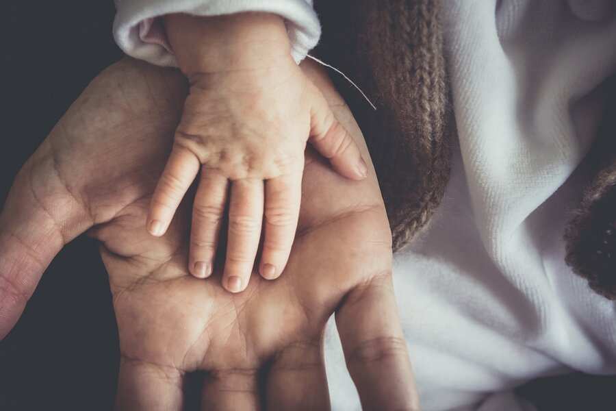 Primer plano de la mano de un bebé apoyada en la palma abierta de un adulto, simbolizando el vínculo puesto de relieve en una reclamación de paternidad. Ambas manos miran hacia arriba, mostrando la diferencia de tamaño. El adulto lleva una manga blanca; el bebé lleva ropa suave. Primer plano de la mano de un bebé apoyada en la palma abierta de un adulto, simbolizando el vínculo puesto de relieve en una reclamación de paternidad. Ambas manos miran hacia arriba, mostrando la diferencia de tamaño. El adulto lleva una manga blanca; el bebé lleva ropa suave.