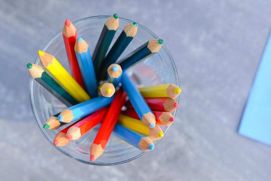 Una vista desde arriba de un vaso de cristal transparente que contiene varios lápices de colores afilados de varios colores, entre ellos rojo, azul, amarillo y verde -que simbolizan opciones como cambiar de escuela hijo sin autorización- sobre un fondo gris difuminado. Una vista desde arriba de un vaso de cristal transparente que contiene varios lápices de colores afilados de varios colores, entre ellos rojo, azul, amarillo y verde -que simbolizan opciones como cambiar de escuela hijo sin autorización- sobre un fondo gris difuminado.