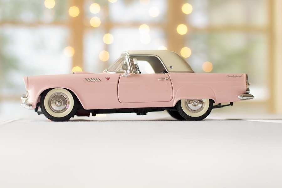 Un modelo de coche de época rosa y blanco, visto de lado, se asienta sobre una superficie clara con un fondo suavemente difuminado, que recuerda los momentos en que uno se pregunta: ¿Quién se queda el coche tras el divorcio?. Un modelo de coche de época rosa y blanco, visto de lado, se asienta sobre una superficie clara con un fondo suavemente difuminado, que recuerda los momentos en que uno se pregunta: ¿Quién se queda el coche tras el divorcio?.