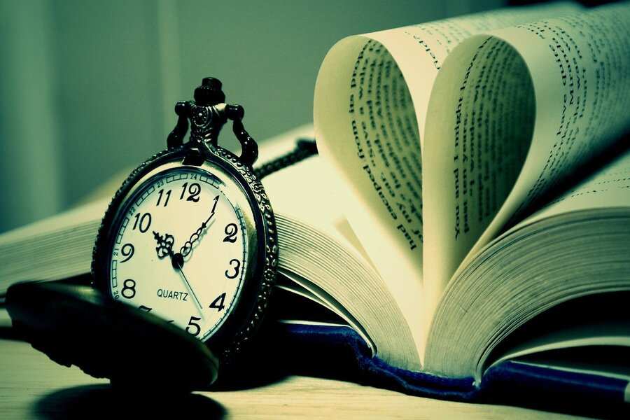Un reloj de bolsillo que marca las 10:10 descansa junto a un libro abierto, con las páginas dobladas en forma de corazón. La imagen, suavemente iluminada con un tono verdoso, evoca sutilmente recuerdos y promesas, al igual que el impacto duradero de la pensión compensatoria.