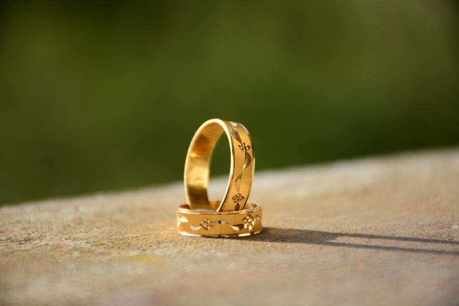 Dos anillos dorados con motivos florales grabados descansan sobre una superficie lisa de color marrón claro, evocando pensamientos de compromiso y la pregunta: ¿puedo negarme a firmar el divorcio? El fondo verde difuminado añade un toque de serenidad. Dos anillos dorados con motivos florales grabados descansan sobre una superficie lisa de color marrón claro, evocando pensamientos de compromiso y la pregunta: ¿puedo negarme a firmar el divorcio? El fondo verde difuminado añade un toque de serenidad.