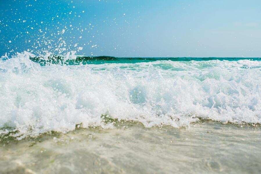 Las olas chocan contra la orilla, creando espuma blanca y salpicaduras. El agua azul y cristalina brilla bajo el cielo brillante, una escena que invita a cualquier campamento de verano después de completar su pago. Las olas chocan contra la orilla, creando espuma blanca y salpicaduras. El agua azul y cristalina brilla bajo el cielo brillante, una escena que invita a cualquier campamento de verano después de completar su pago.