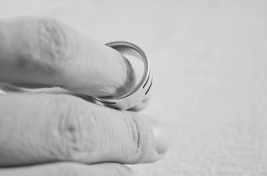 Primer plano en blanco y negro de una mano con un anillo que se desprende de un dedo sobre un fondo liso. La foto capta sutilmente el momento emotivo de un anillo retirado tras un divorcio de mutuo acuerdo. Primer plano en blanco y negro de una mano con un anillo que se desprende de un dedo sobre un fondo liso. La foto capta sutilmente el momento emotivo de un anillo retirado tras un divorcio de mutuo acuerdo.
