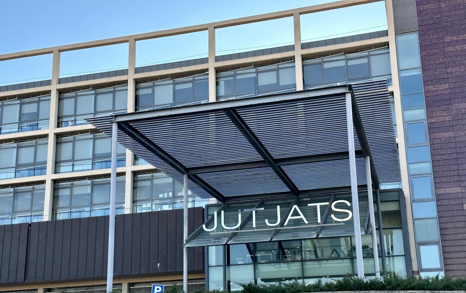 Un edificio moderno con grandes ventanales de cristal y un toldo metálico muestra la palabra JUTJATS en grandes letras blancas sobre la entrada, señalándolo como uno de los principales juzgados de Terrassa.