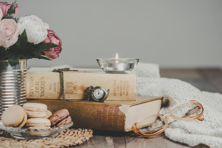 Una pila de libros antiguos sobre una superficie de madera con un reloj de bolsillo, una vela de cristal, un jarrón de flores, macarons y gafas cerca, crean un ambiente sereno perfecto para reflexionar sobre cambios como un divorcio notarial. Una pila de libros antiguos sobre una superficie de madera con un reloj de bolsillo, una vela de cristal, un jarrón de flores, macarons y gafas cerca, crean un ambiente sereno perfecto para reflexionar sobre cambios como un divorcio notarial.